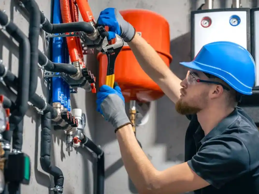 Technician inspecting a supply line or hose connection behind a kitchen or laundry — Appliance Leak Cleanup in Fairfax, VA