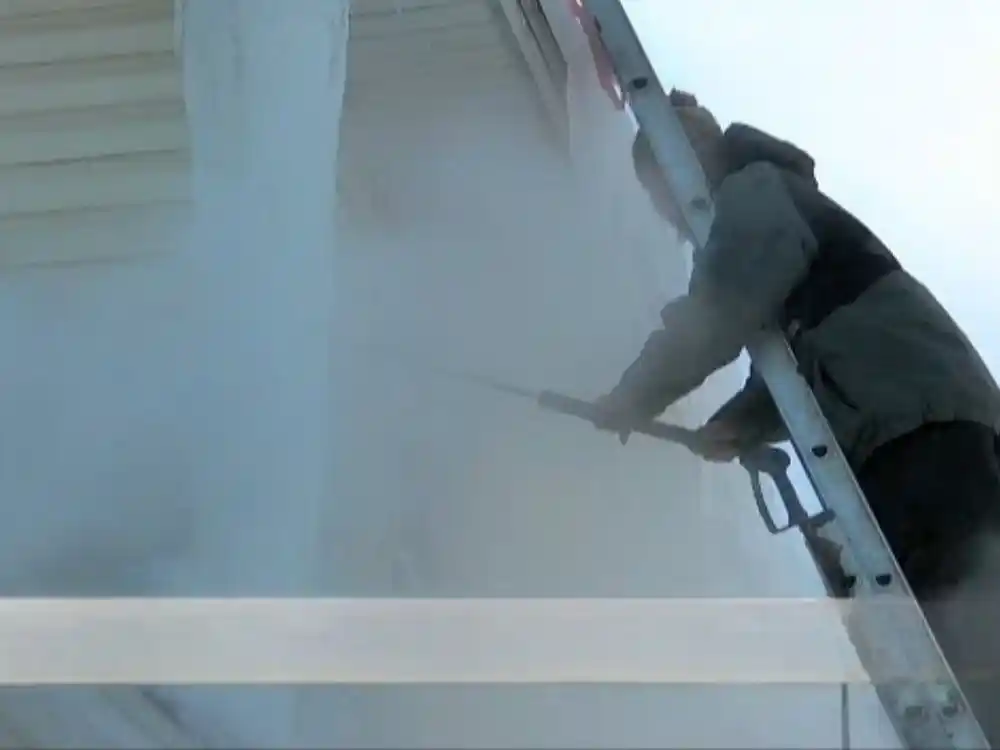 Technician using a steam machine to safely melt and remove an ice dam from a roof edge — Ice Dam Removal Repair in Fairfax, VA