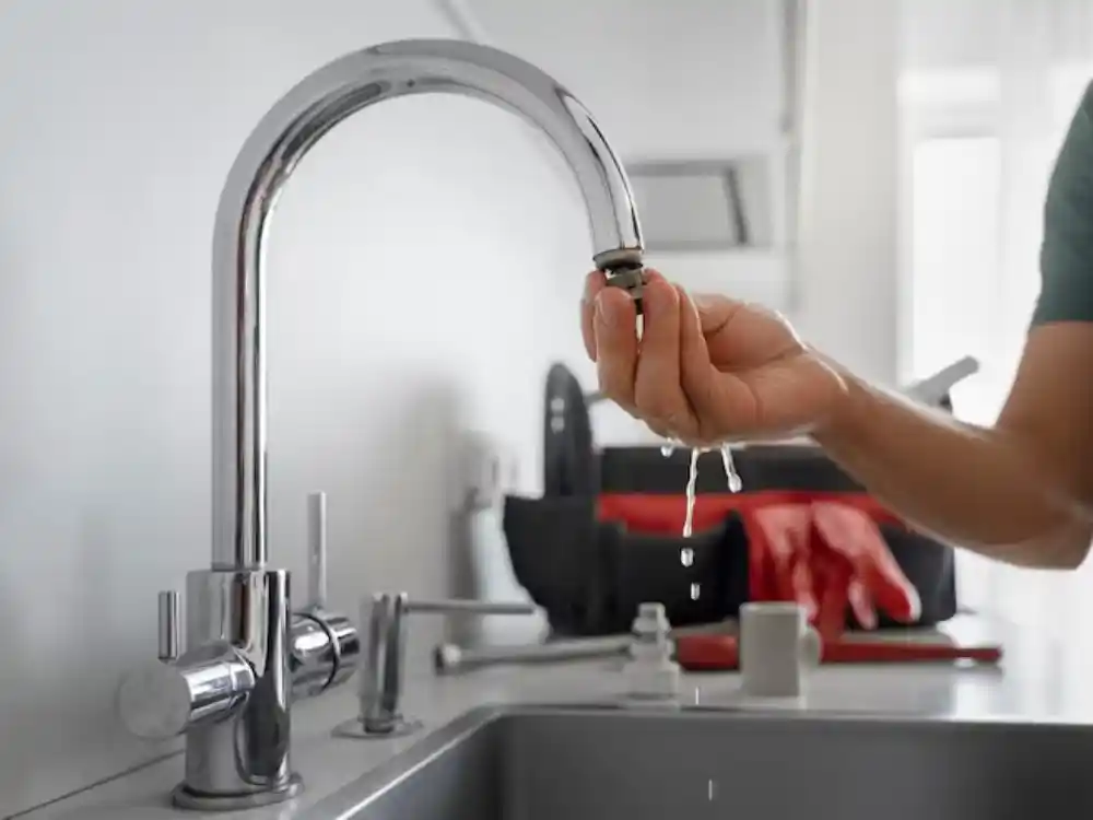 Technician shutting off a fixture's angle-stop valve under a sink as a first-response step — Plumbing Overflow Cleanup in Fairfax, VA
