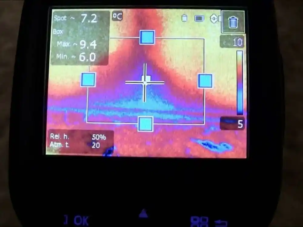 Close-up of a thermal imaging camera screen showing a cold/wet spot pattern on a wall or — Water Damage Inspection in Fairfax, VA